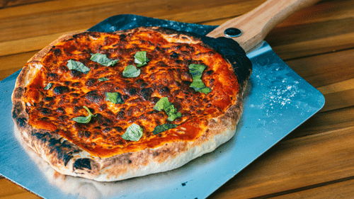 A full pizza just taken out of the oven and kept on the table