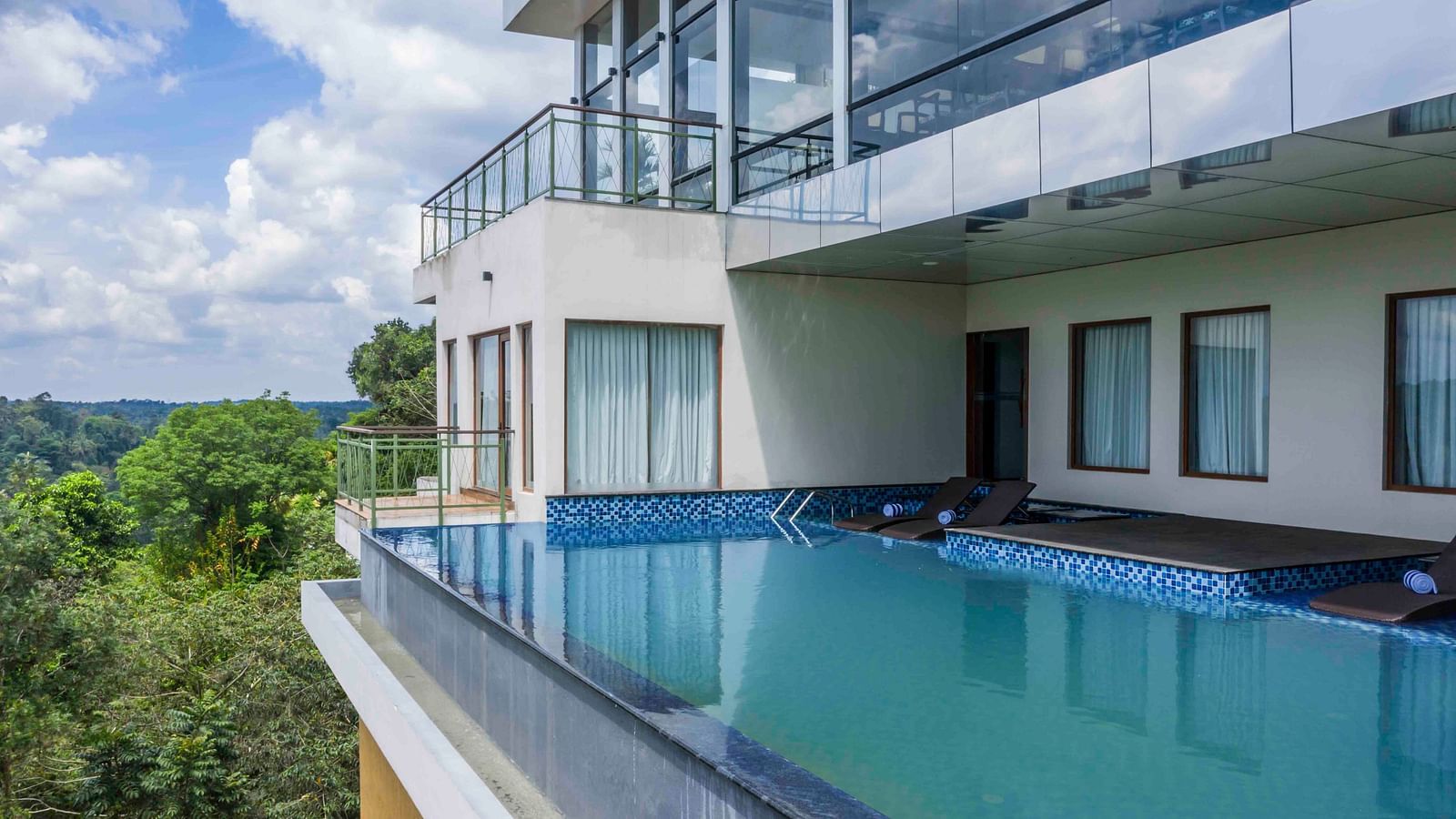 Image of the infinity pool overlooking the clear sky and the greenery all around.| Great Trails Wayanad by  GRT hotels.