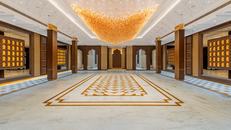 Symmetrical view of the banquet hall at EsthereaRaj Leela, Ranakpur, featuring wooden pillars, decorative wall panels, and an ornate ceiling.