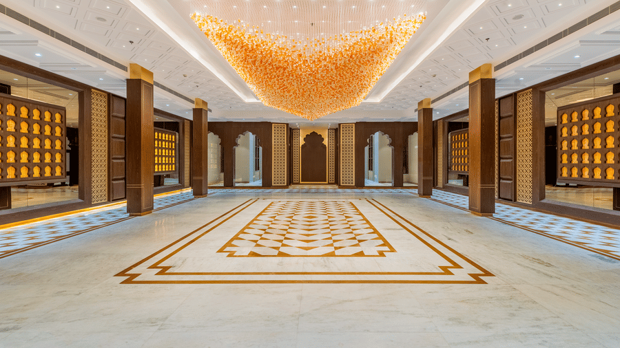Symmetrical view of the banquet hall at EsthereaRaj Leela, Ranakpur, featuring wooden pillars, decorative wall panels, and an ornate ceiling.