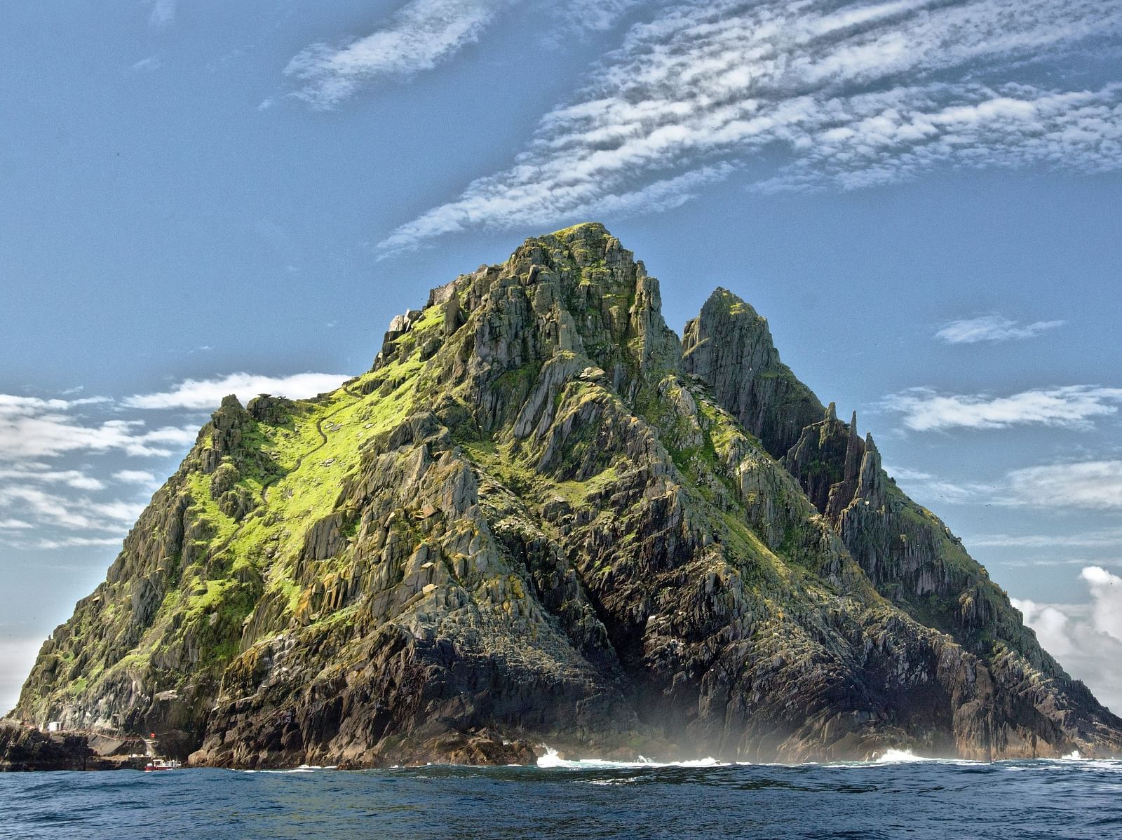 An image of a lush green mountain with fog forming at the bottom of the mountain