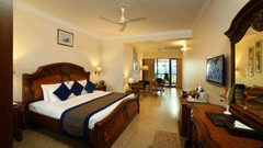The Premium Sea View Room at Uday Samudra Leisure Beach Hotel offers a spacious bedroom with a king size bed, a separate living area with a television, and a balcony.