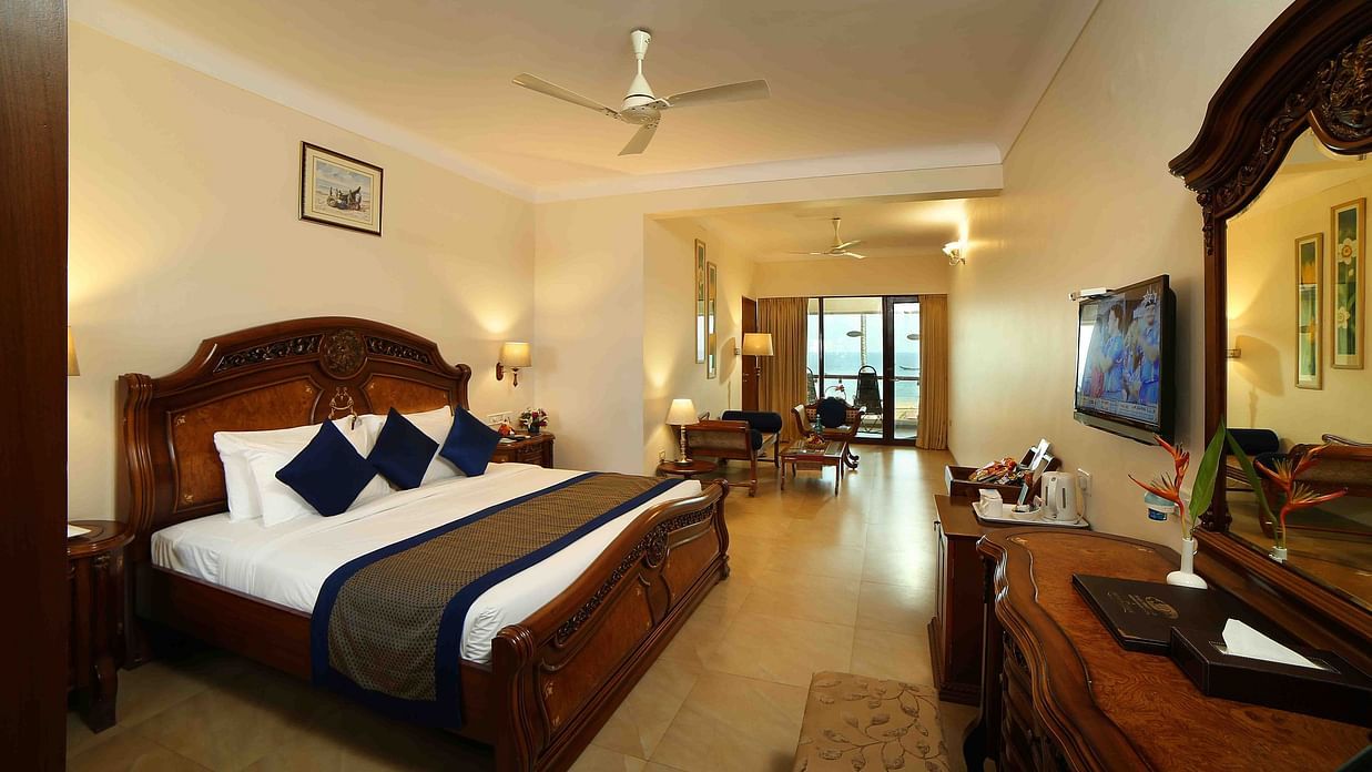 The Premium Sea View Room at Uday Samudra Leisure Beach Hotel offers a spacious bedroom with a king size bed, a separate living area with a television, and a balcony.