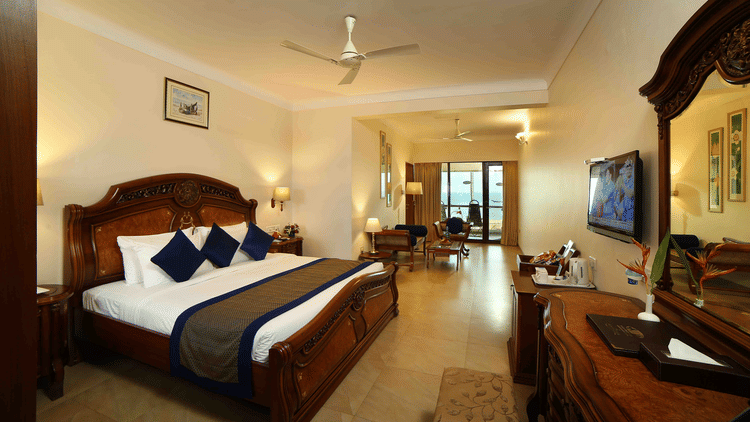 The Premium Sea View Room at Uday Samudra Leisure Beach Hotel offers a spacious bedroom with a king size bed, a separate living area with a television, and a balcony.
