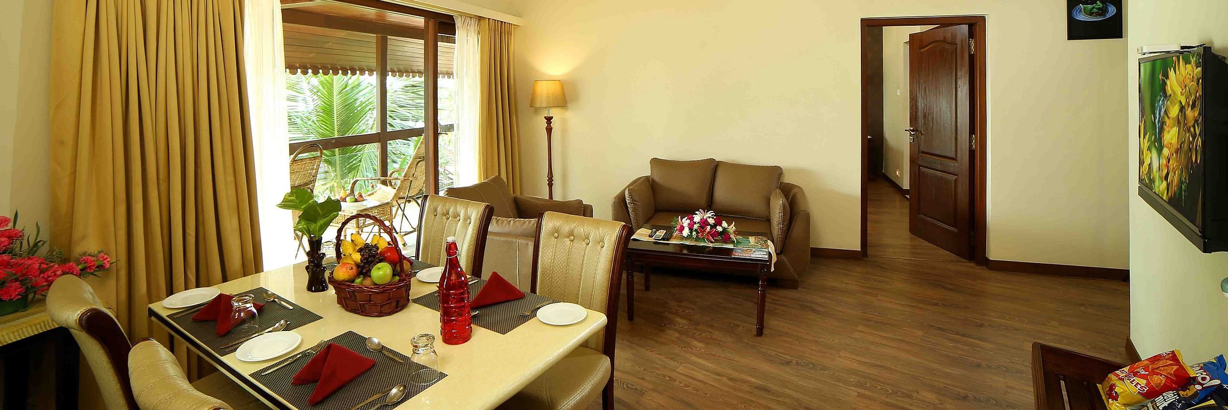 The Ocean Breeze Suite at Uday Samudra Leisure Beach Hotel features a dining area, a lounge with a sofa, and a doorway
