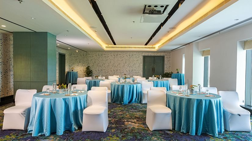 Round table seating with blue sheets on the table and white sheets on the chairs - Karma Lakelands.