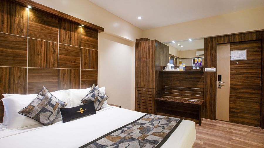 A close view of the Deluxe room at Hotel Bawa Regency, Dadar, focusing on the comfy bed, wardrobe, and kettle with sugar and other amenities.