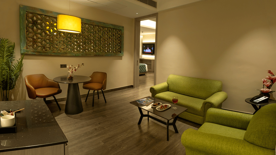 Inviting living area with green sofas and tasteful lighting at The Sonnet, Jamshedpur.