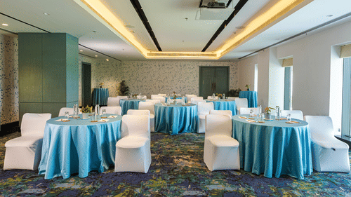 Round table seating with blue sheets on the table and white sheets on the chairs - Karma Lakelands.