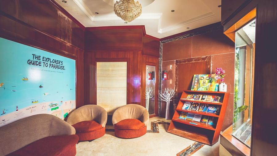 Indoor reading area with chairs and a magazine stand at Paradise Isle Beach Resort, Udupi