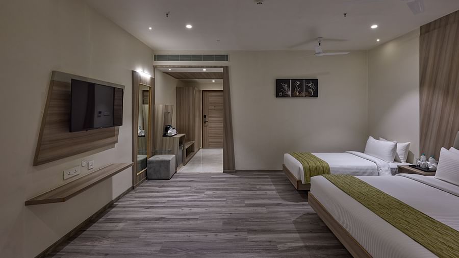 A king bed, single bed and tv wall mounted inside family room at Grand Continent - A Sarovar Premiere Affiliate Hotel, Hosur