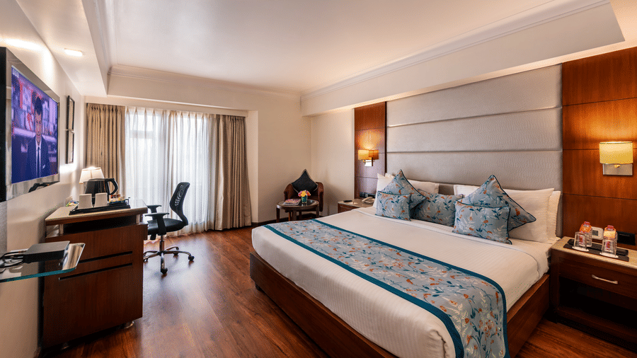 Cosy club room with a double bed, wooden flooring,good ventilation and a small desk at Lords Plaza Jaipur.
