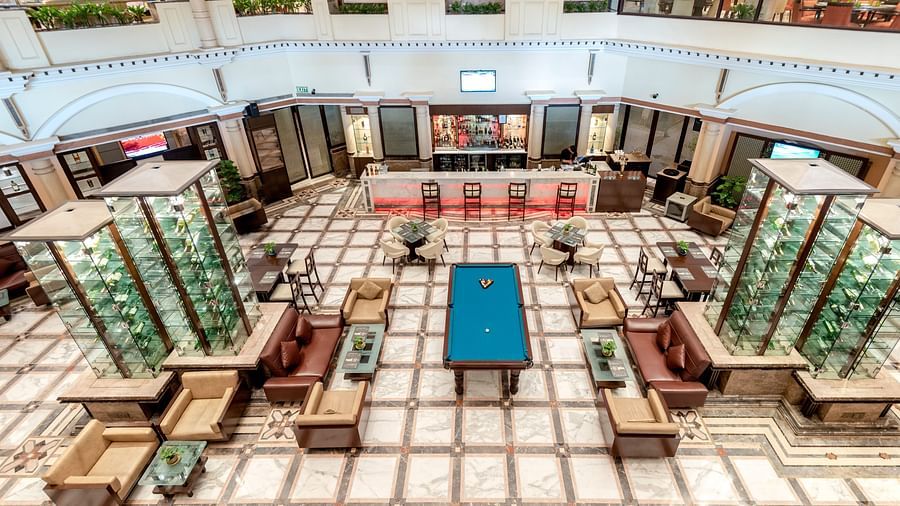An image of a bar with many multi storey glass cabinet where liquor bottles are kept - The Suryaa New Delhi