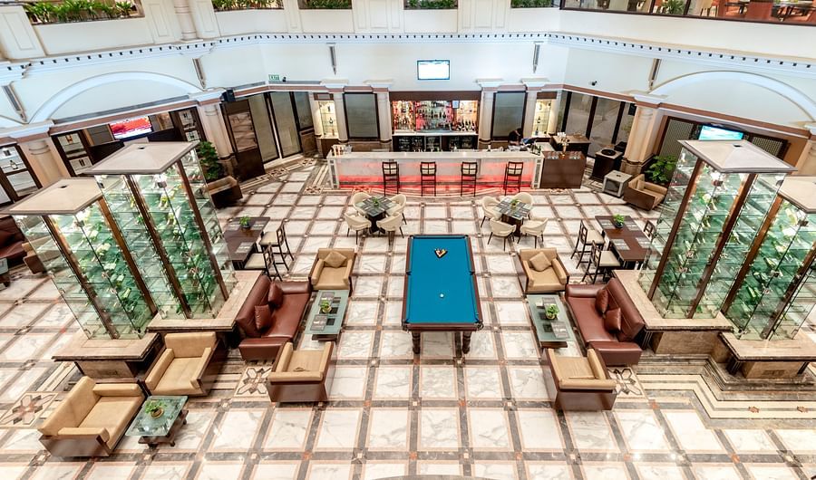 An image of a bar with many multi storey glass cabinet where liquor bottles are kept - The Suryaa New Delhi