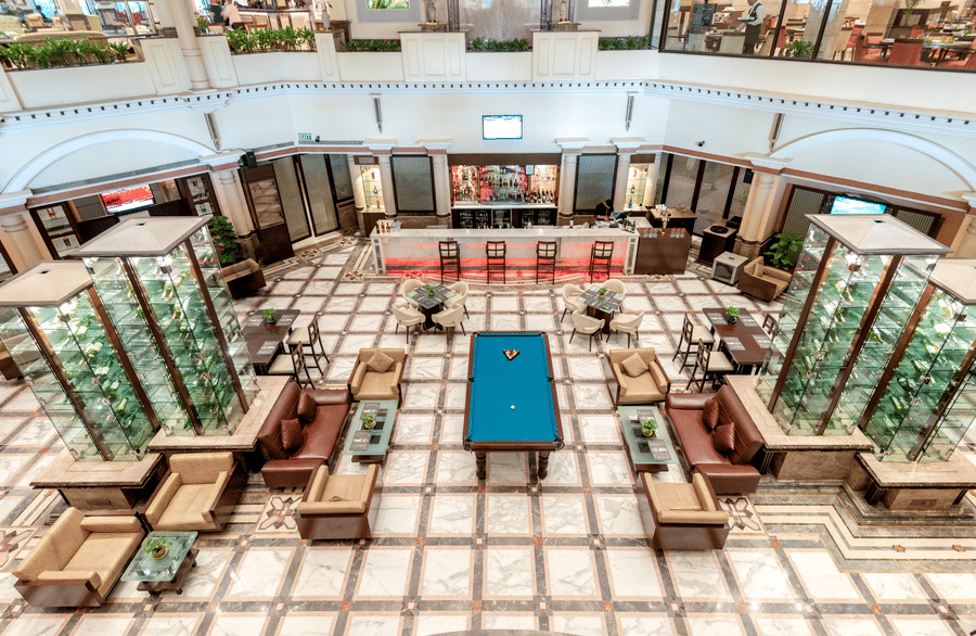 An image of a bar with many multi storey glass cabinet where liquor bottles are kept - The Suryaa New Delhi