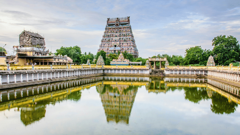 A grand South Indian temple with towering gopurams and a sacred water tank reflecting its intricate architecture.