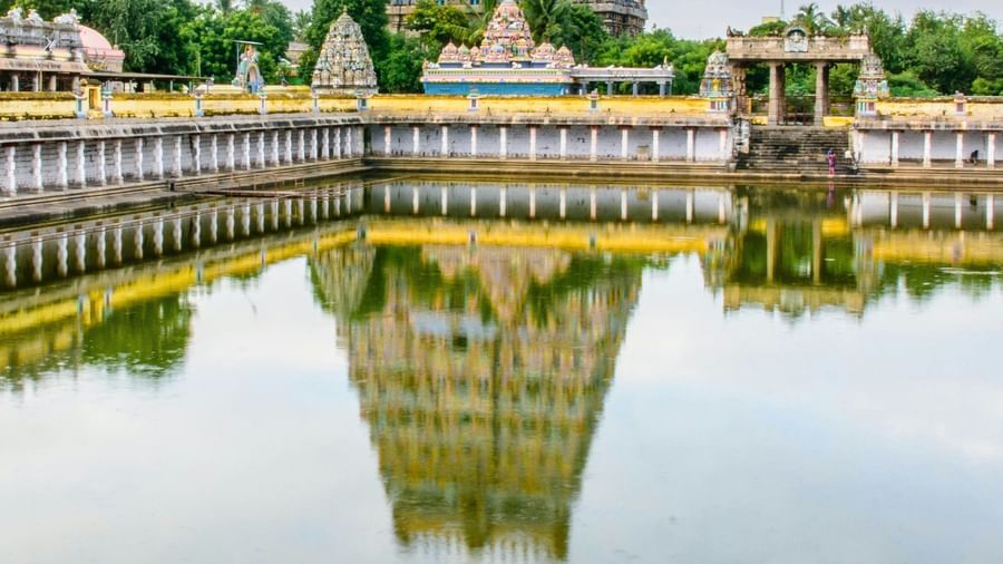 A grand South Indian temple with towering gopurams and a sacred water tank reflecting its intricate architecture.