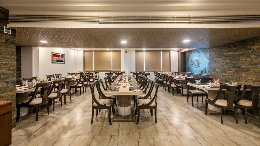 A spacious and well-lit restaurant dining area with multiple tables and chairs arranged for guests.