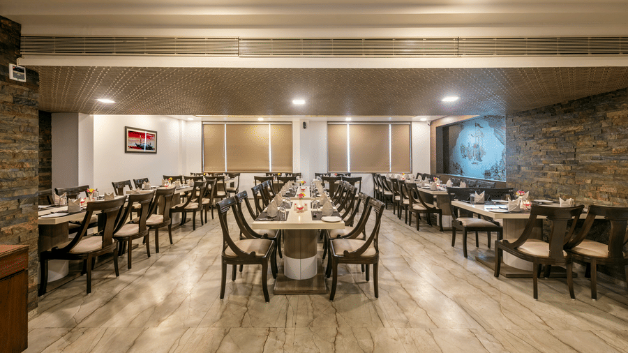 A spacious and well-lit restaurant dining area with multiple tables and chairs arranged for guests.