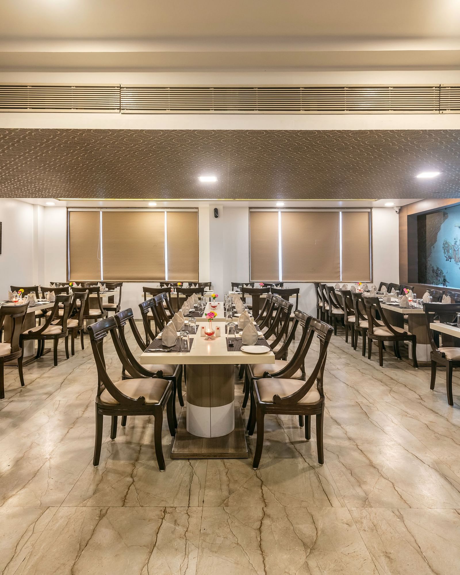 A spacious and well-lit restaurant dining area with multiple tables and chairs arranged for guests.