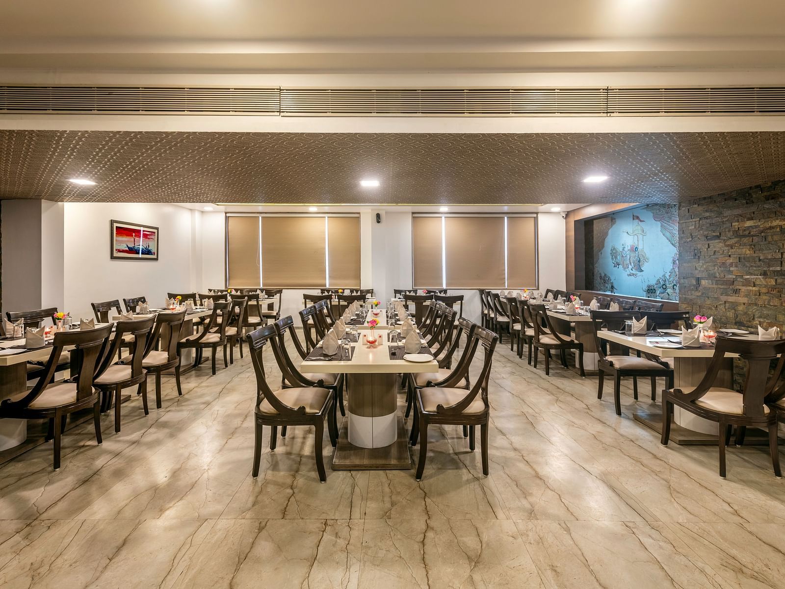 A spacious and well-lit restaurant dining area with multiple tables and chairs arranged for guests.