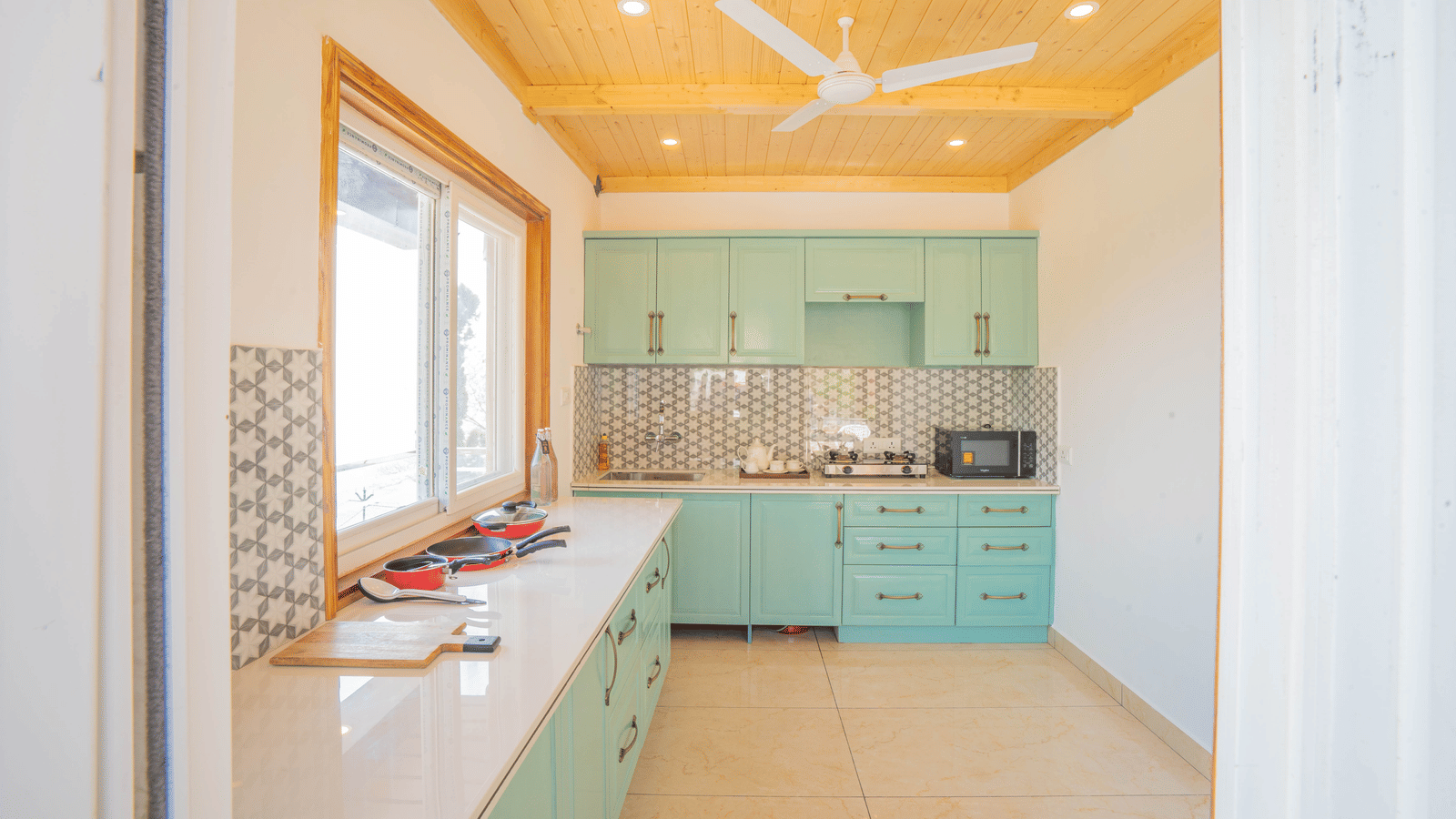 A kitchen area featuring cabinets, a sink, and a countertop equipped with appliances and cookware at Perfectstayz Value Paradise, Mussoorie.