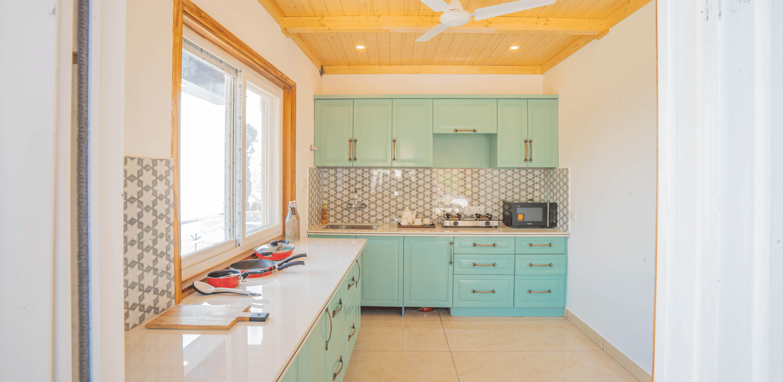 A kitchen area featuring cabinets, a sink, and a countertop equipped with appliances and cookware at Perfectstayz Value Paradise, Mussoorie.