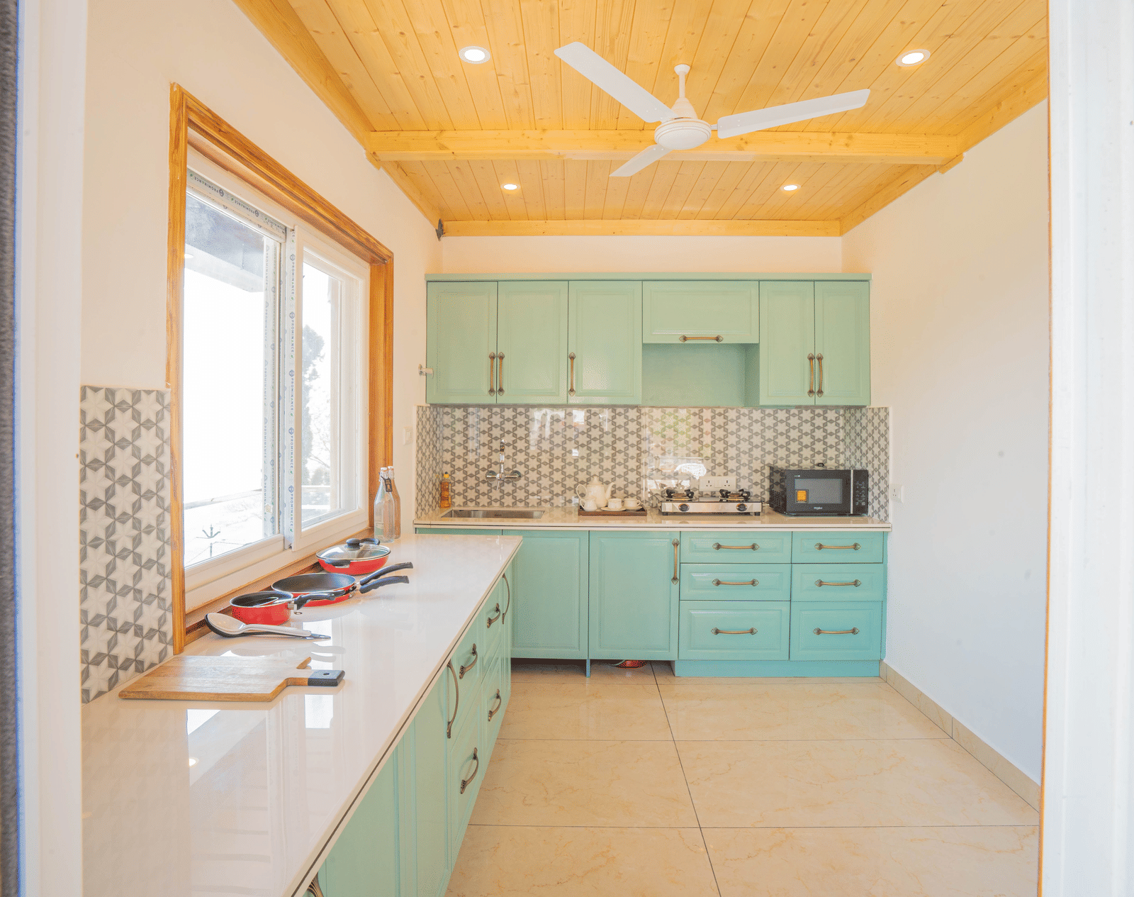 A kitchen area featuring cabinets, a sink, and a countertop equipped with appliances and cookware at Perfectstayz Value Paradise, Mussoorie.