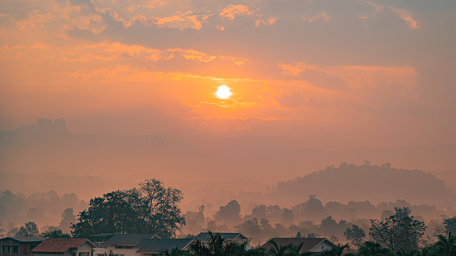 A scenic sunrise over a misty landscape with distant hills at Lotus Leaf Boutique Hotel.