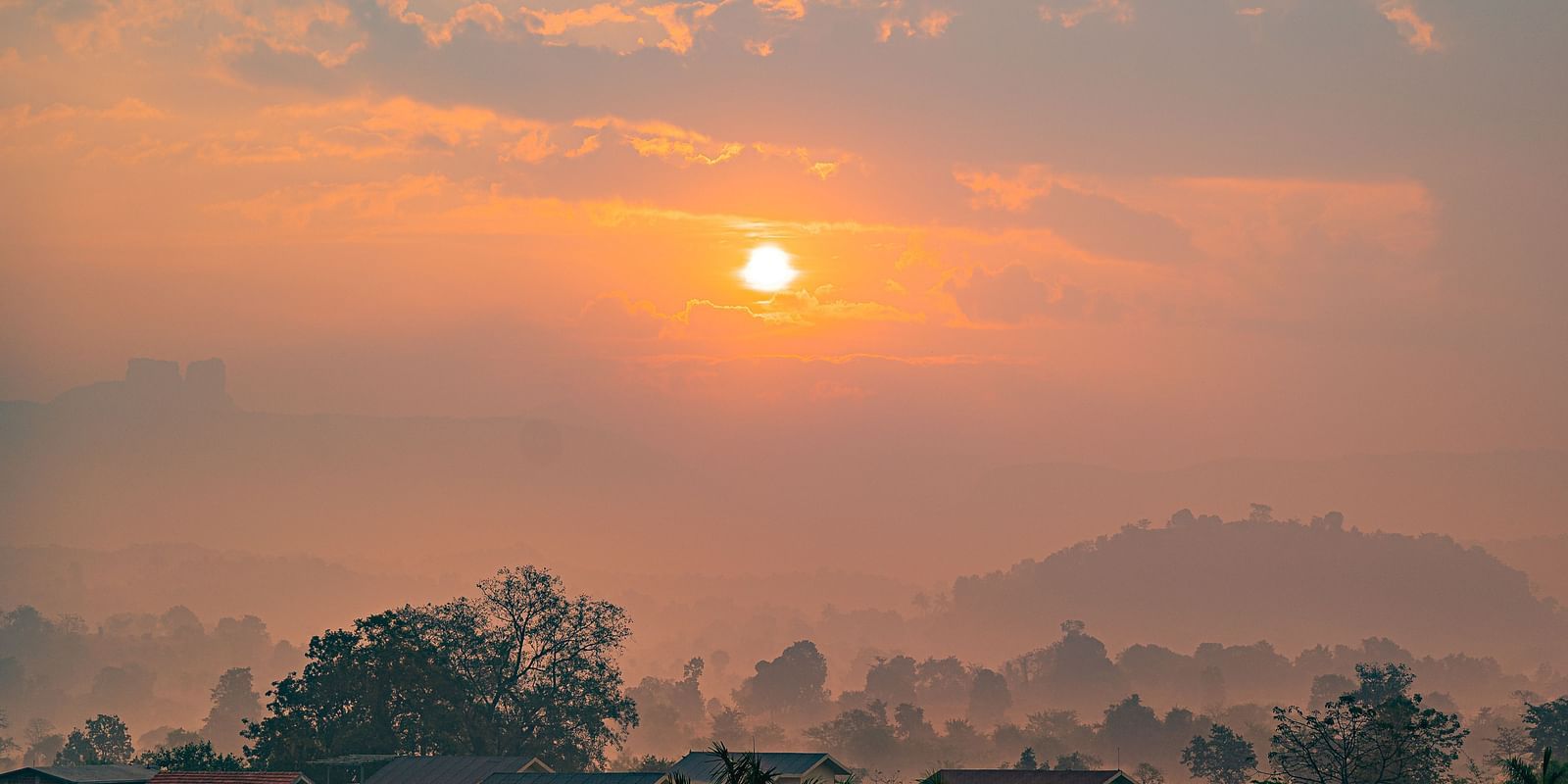 A scenic sunrise over a misty landscape with distant hills at Lotus Leaf Boutique Hotel.