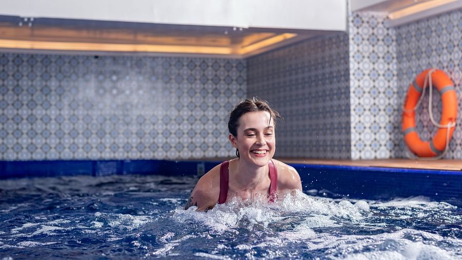 A woman enjoying a swim in the indoor pool - The Claridges New Delhi