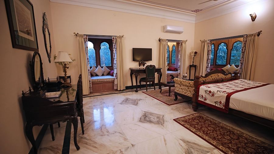 An inviting hotel bedroom with a large bed, dressing table, and traditional Indian decor - Khas Bagh, Jaipur.