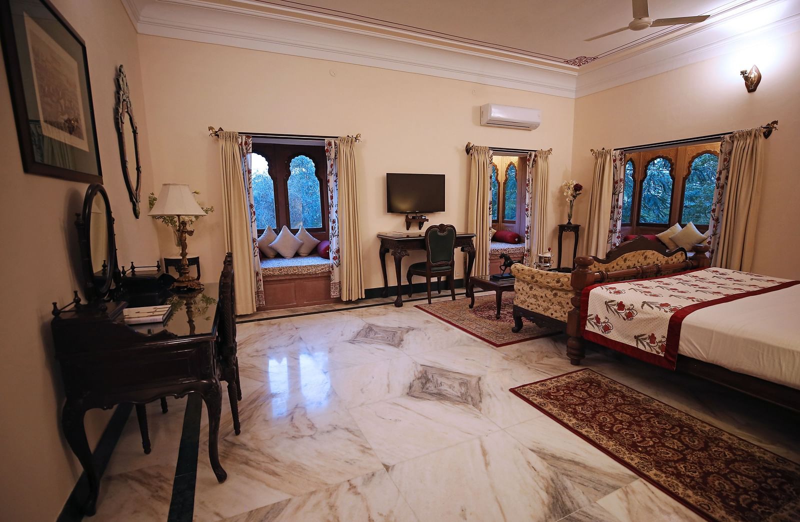 An inviting hotel bedroom with a large bed, dressing table, and traditional Indian decor - Khas Bagh, Jaipur.