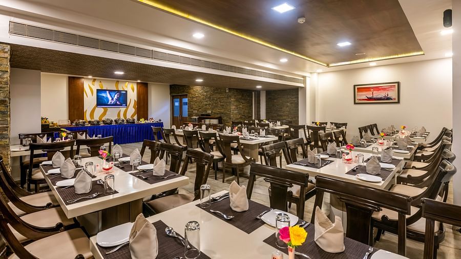 A brightly lit restaurant at Dwarkadhish Lords Eco Inn with neatly arranged tables and chairs, ready for diners.