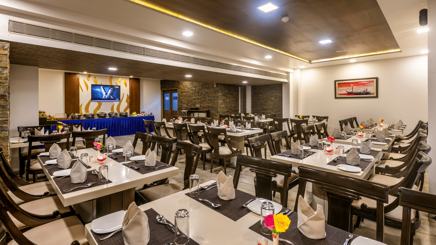 A brightly lit restaurant at Dwarkadhish Lords Eco Inn with neatly arranged tables and chairs, ready for diners.