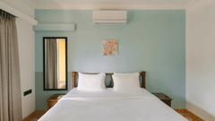 Comfortable king-size bed with pastel interiors at One BHK Apartment, Richmonde Ananta Elite, Goa.