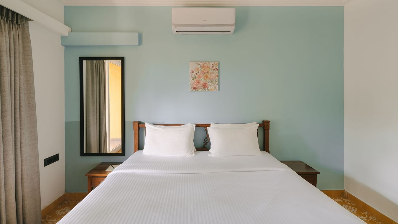 Comfortable king-size bed with pastel interiors at One BHK Apartment, Richmonde Ananta Elite, Goa.