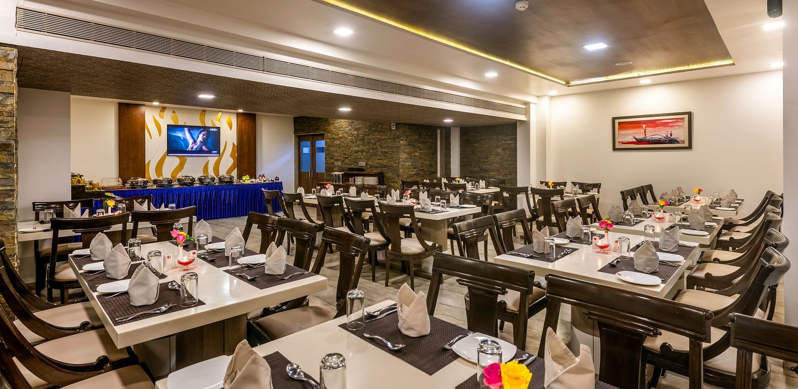 A brightly lit restaurant at Dwarkadhish Lords Eco Inn with neatly arranged tables and chairs, ready for diners.