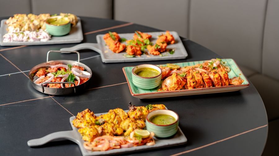 Table laden with multiple platters of appetizers and dipping sauces | Pravasa Hotel, Vijayapura