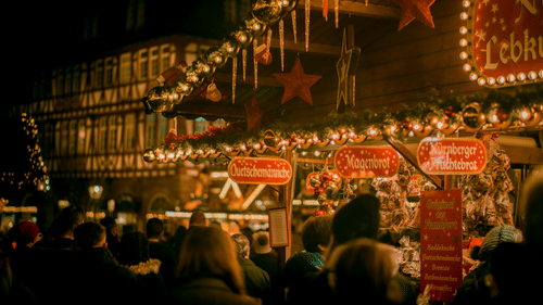 A Christmas market with shops selling Christmas themed items and people frolicking to buy them