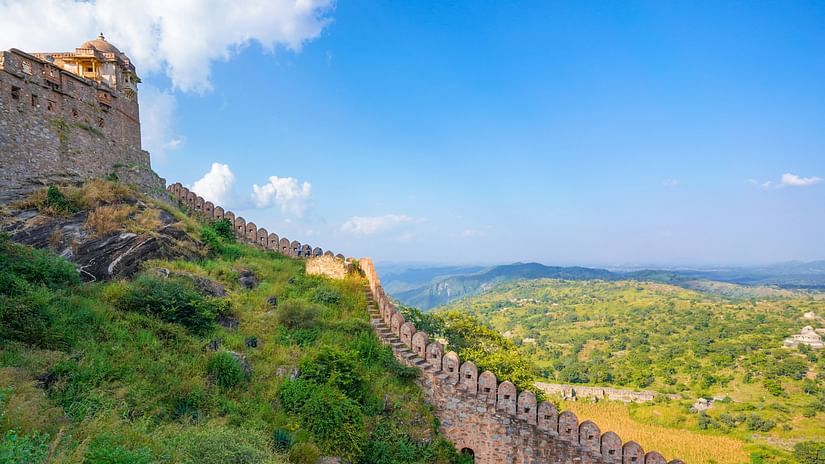 A long and continuous stone wall surrounded by lush greenery on a hill