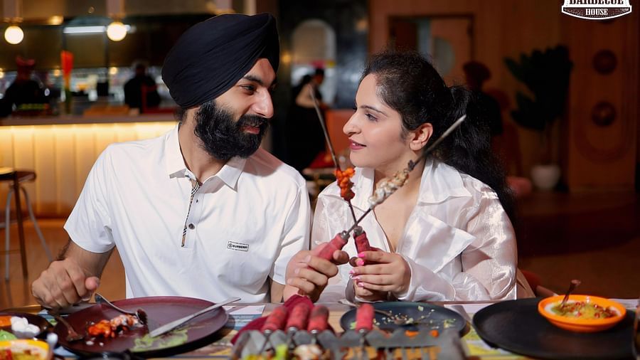 An image of a couple staring at each other while holder barbecue skewer at Themis Barbecue House, Ambala