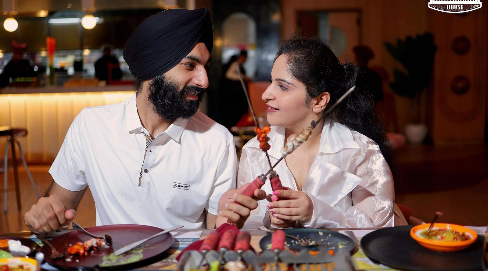 An image of a couple staring at each other while holder barbecue skewer at Themis Barbecue House, Ambala