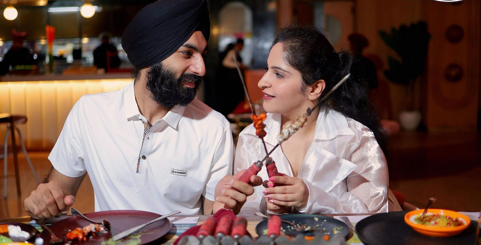 An image of a couple staring at each other while holder barbecue skewer at Themis Barbecue House, Ambala