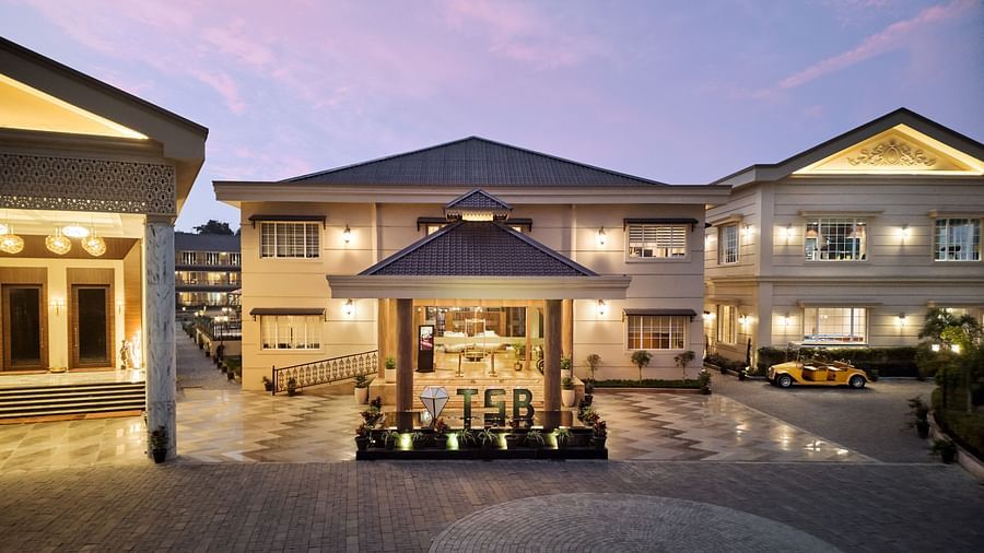 Elegant hotel entrance at dusk with warm lighting, a tiled driveway, and a vintage yellow car parked on the right - Voyage The Solitaire Bliss.