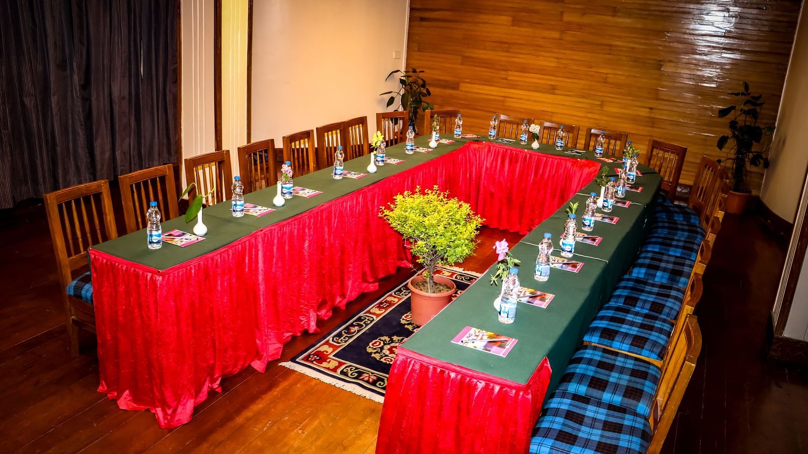 U-Shape seating arrangement in the Banquet hall of Cedar Inn, Darjeeling set up with notepads, water bottles, chairs and overhead lighting.