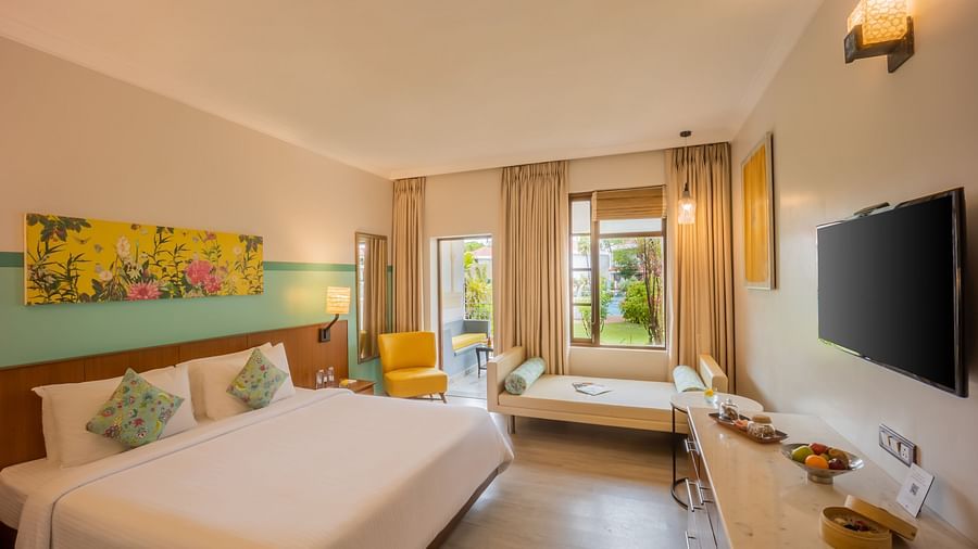 room with a king size bed and vibrant yellow interiors at Heritage Village Resorts and spa
