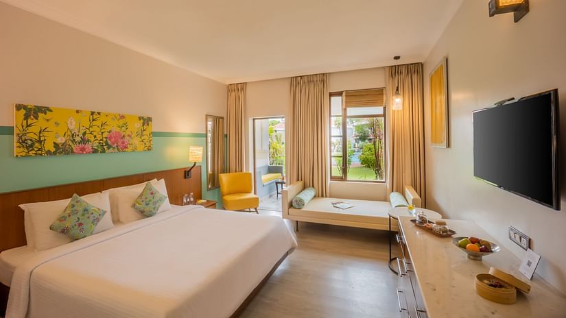 room with a king size bed and vibrant yellow interiors at Heritage Village Resorts and spa