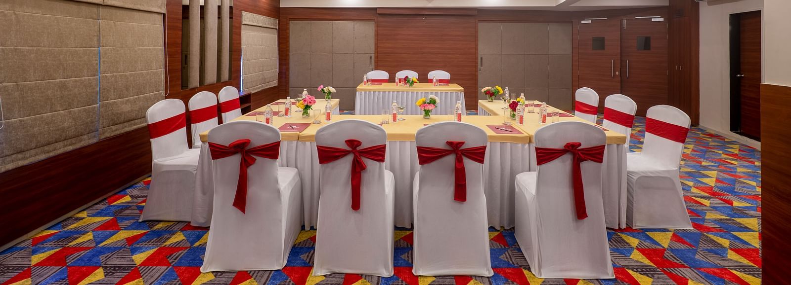 A well lit conference room setup with a central table arrangement in Lords Eco Inn Shapar Rajkot