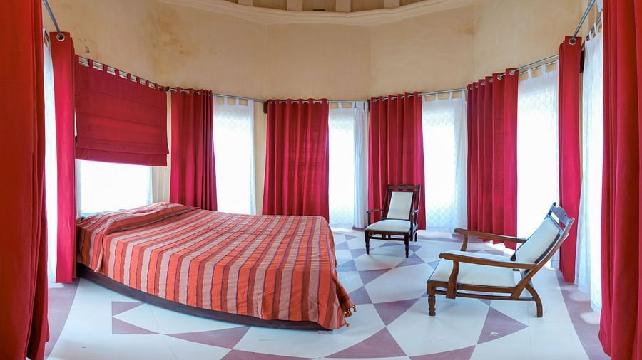 A circular room with a bed, two chairs, and many curtains in Tijara Fort-Palace - 19th Century, Alwar.